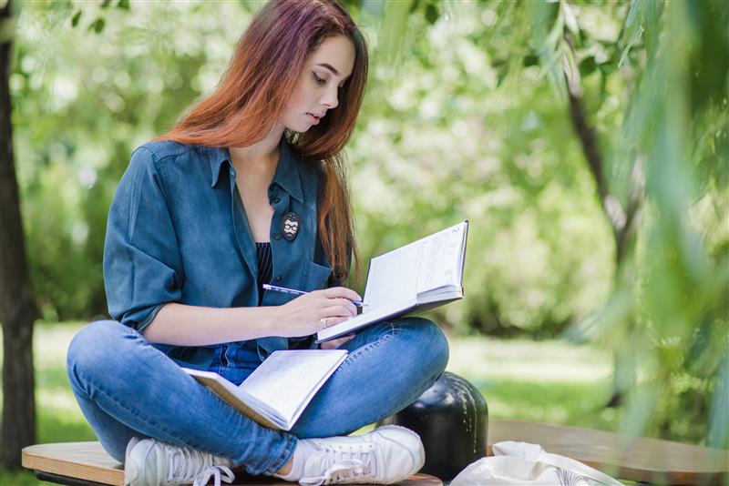 girl-sitting-park-table-reading